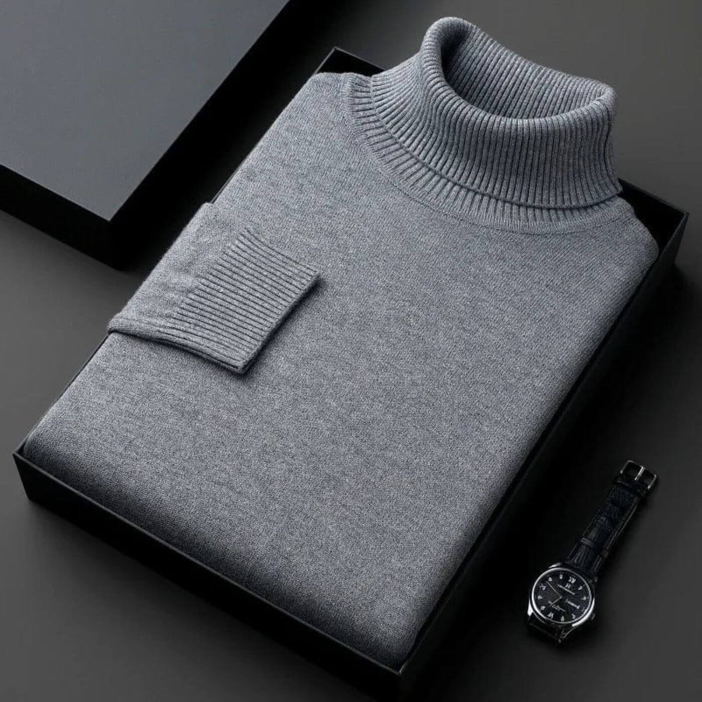 Pull à col roulé gris foncé moderne, soigneusement emballé dans une boîte élégante. Maille douce et chaude.